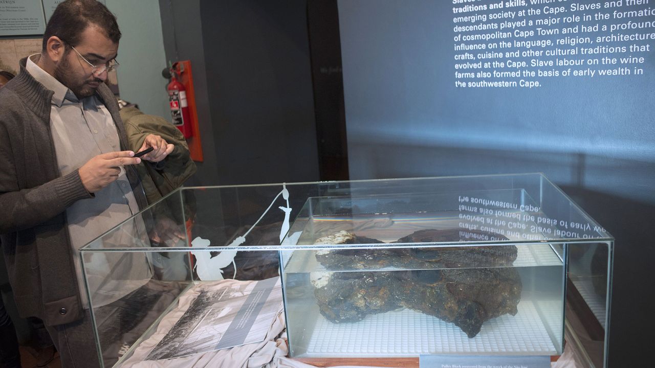 A man takes a picture of a pulley block, one of several recovered artefacts brought up from sunken São José.