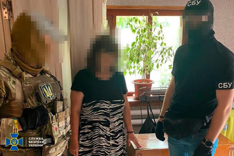 A woman, center, being detained by law enforcement after she was accused of plotting to assassinate President Volodymyr Zelenskyy.