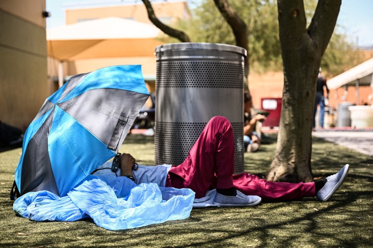 Image: A Phoenix resident rests under shade while seeking protection from the sun and heat at the Human Services Campus during a record heat wave in Phoenix on July 18, 2023.