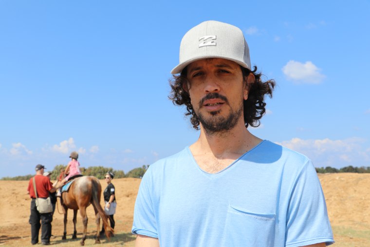 Eilon Kotler with his daughter, who can be seen learning how to ride a horse, behind him.