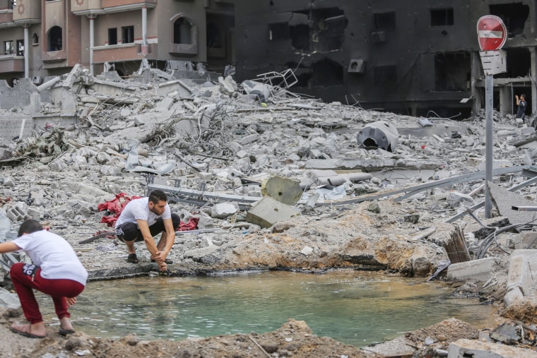 Palestinian man washes his hands in a puddle beside a