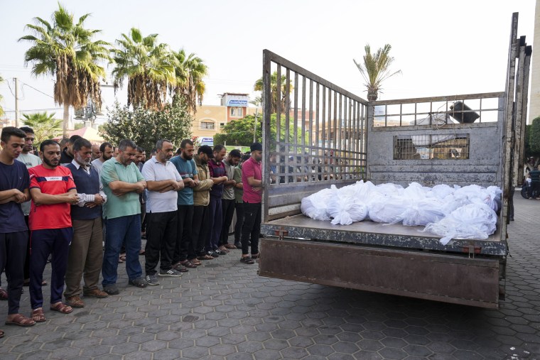 Friends and relatives pray by the bodies of the dead at Al-Aqsa Hospital in Deir Al-Balah, Gaza.