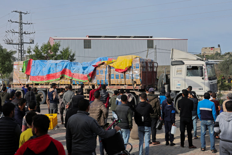 Images: An aid truck moves on a road as Palestinians look on