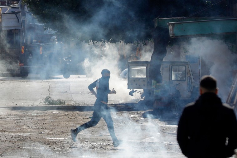 Palestinian protesters run from from tear gas during a raid by Israeli security forces in the Balata refugee camp in the occupied West Bank on Nov. 21, 2023.