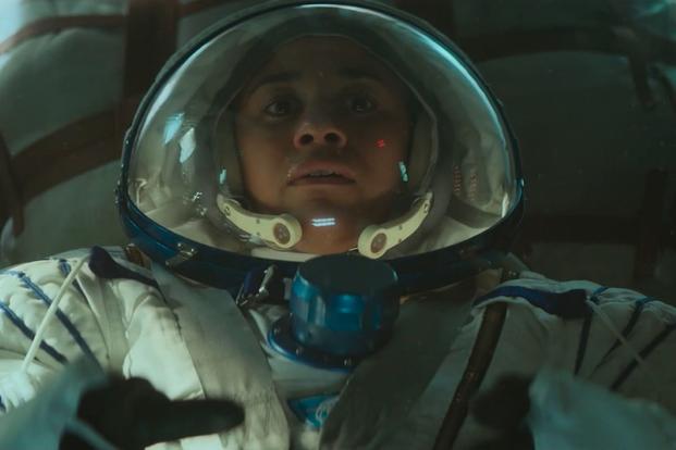 A closeup of an actor portraying an astronaut looking tense inside a space helmet.