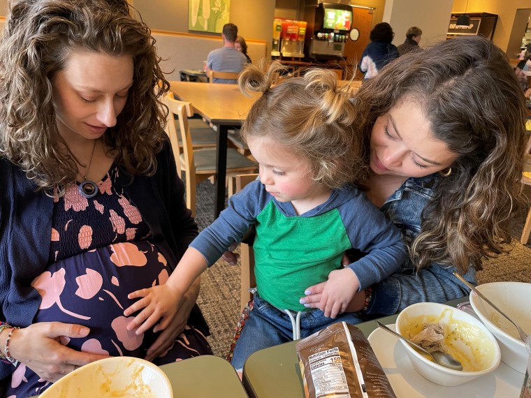 Alex Kamer's older son touches the pregnant belly of Zientek, who served as the surrogate for the new baby.