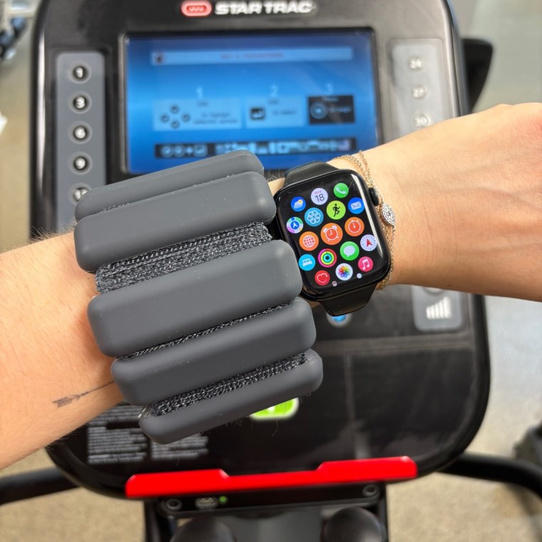 Woman’s arm in a gym with a black Bala Bangle and an Apple Watch on it.