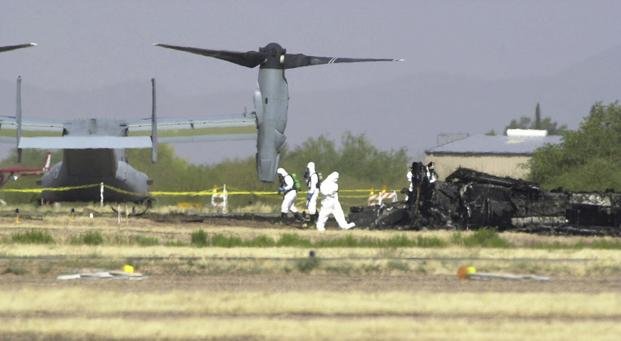 White suited workers investigate the crash scene of a Marine Corps MV-22 Osprey at the Avra Valley Airport